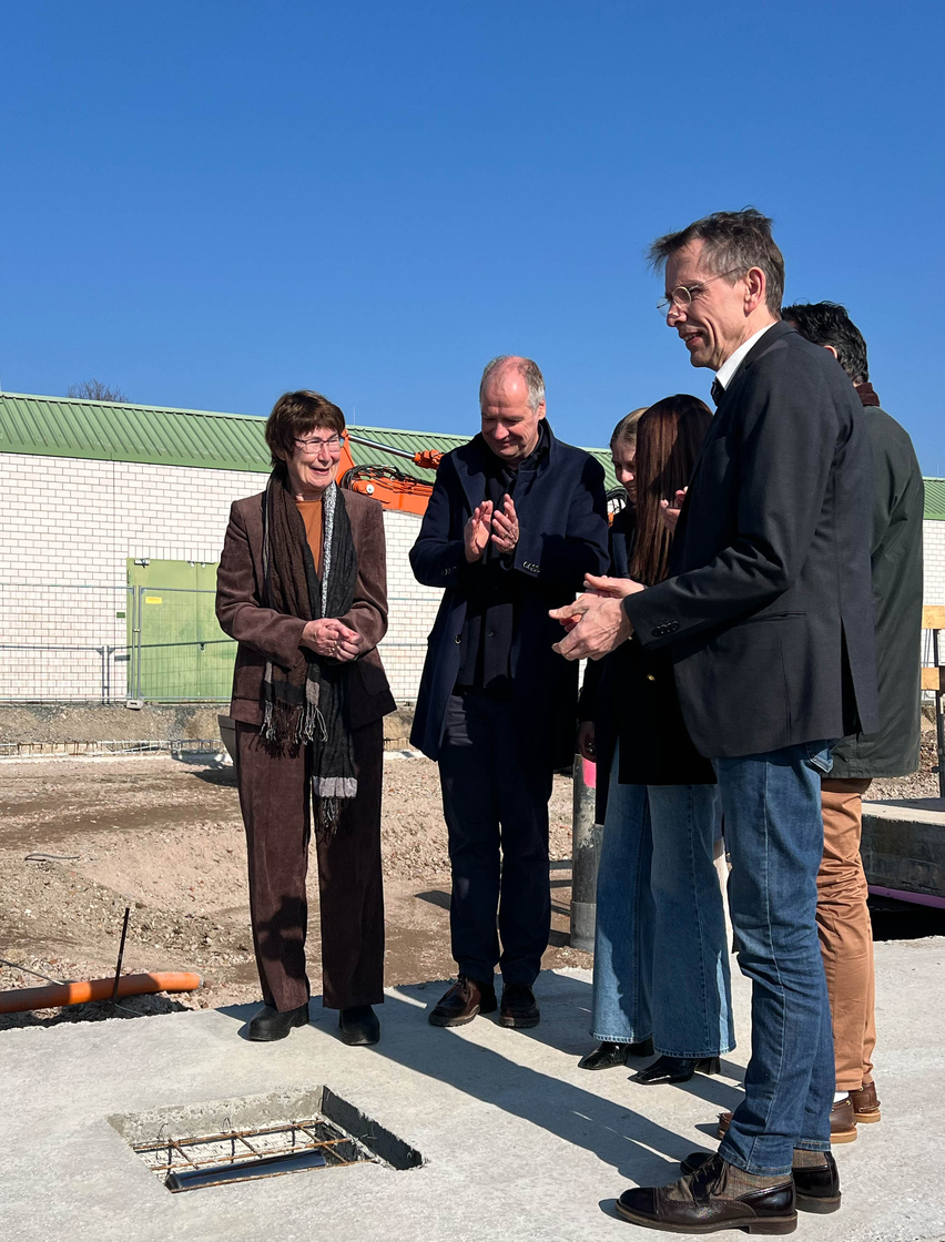 Vertreter von Stadt, Schule und Architekturbüro verlegen eine Zeitkapsel